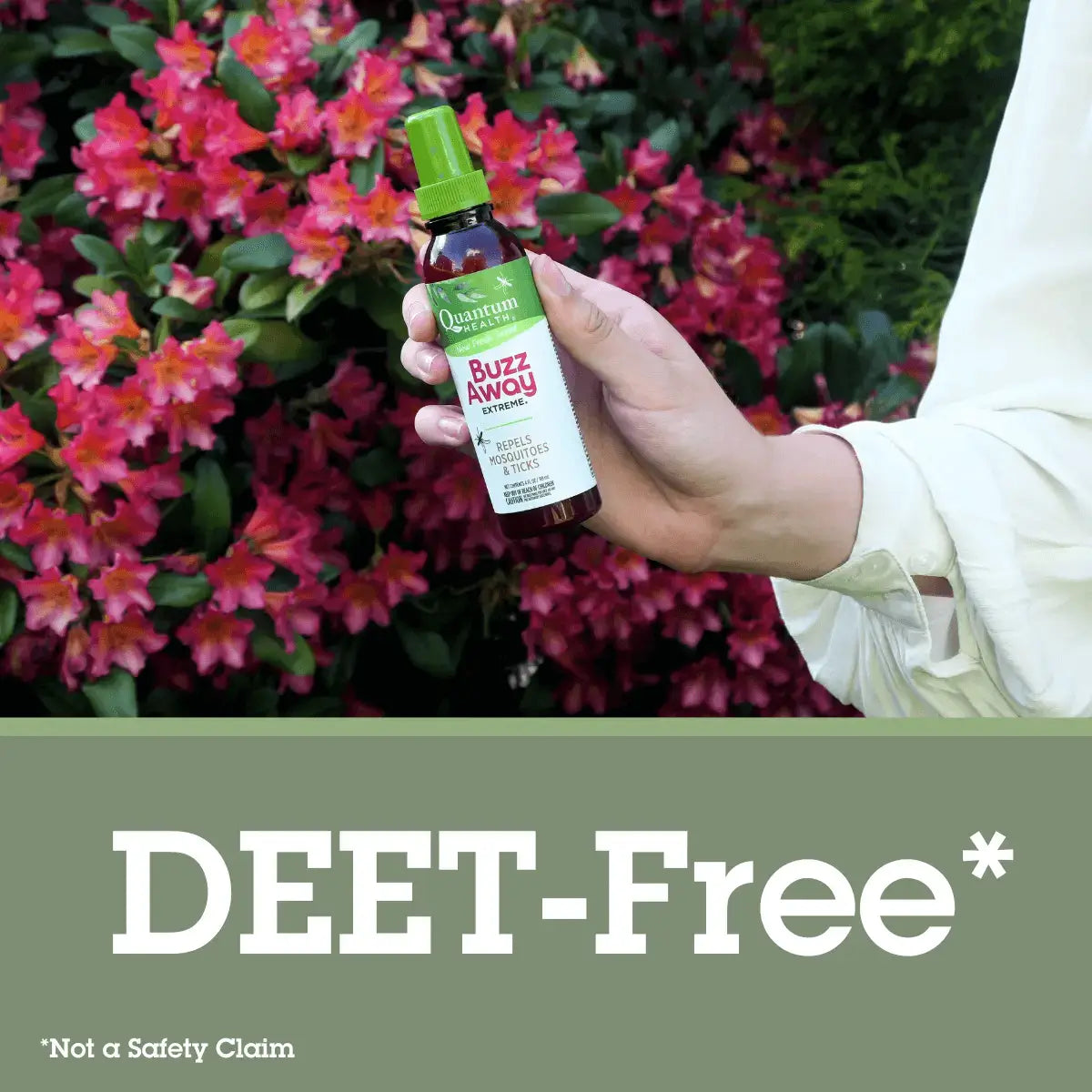 Hand holding a bottle of 'Buzz Away'DEET-Free insect repellent with flowers in the background