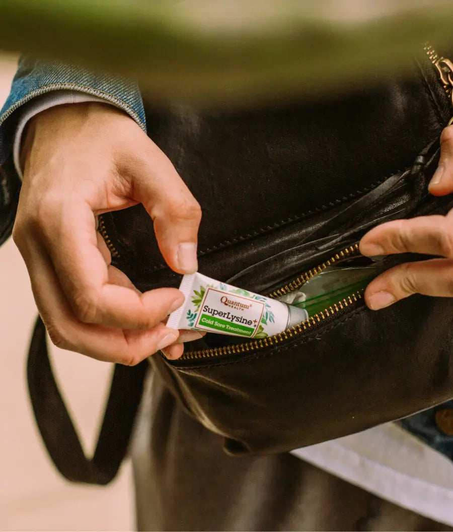 Person retrieving SuperLysine+ Cold Sore Treatment from a black leather bag