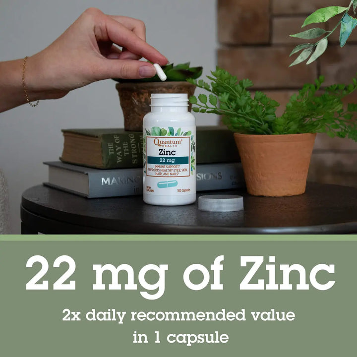 Supplement bottle labeled '22 mg of Zinc' on a table with books and plants in the background.