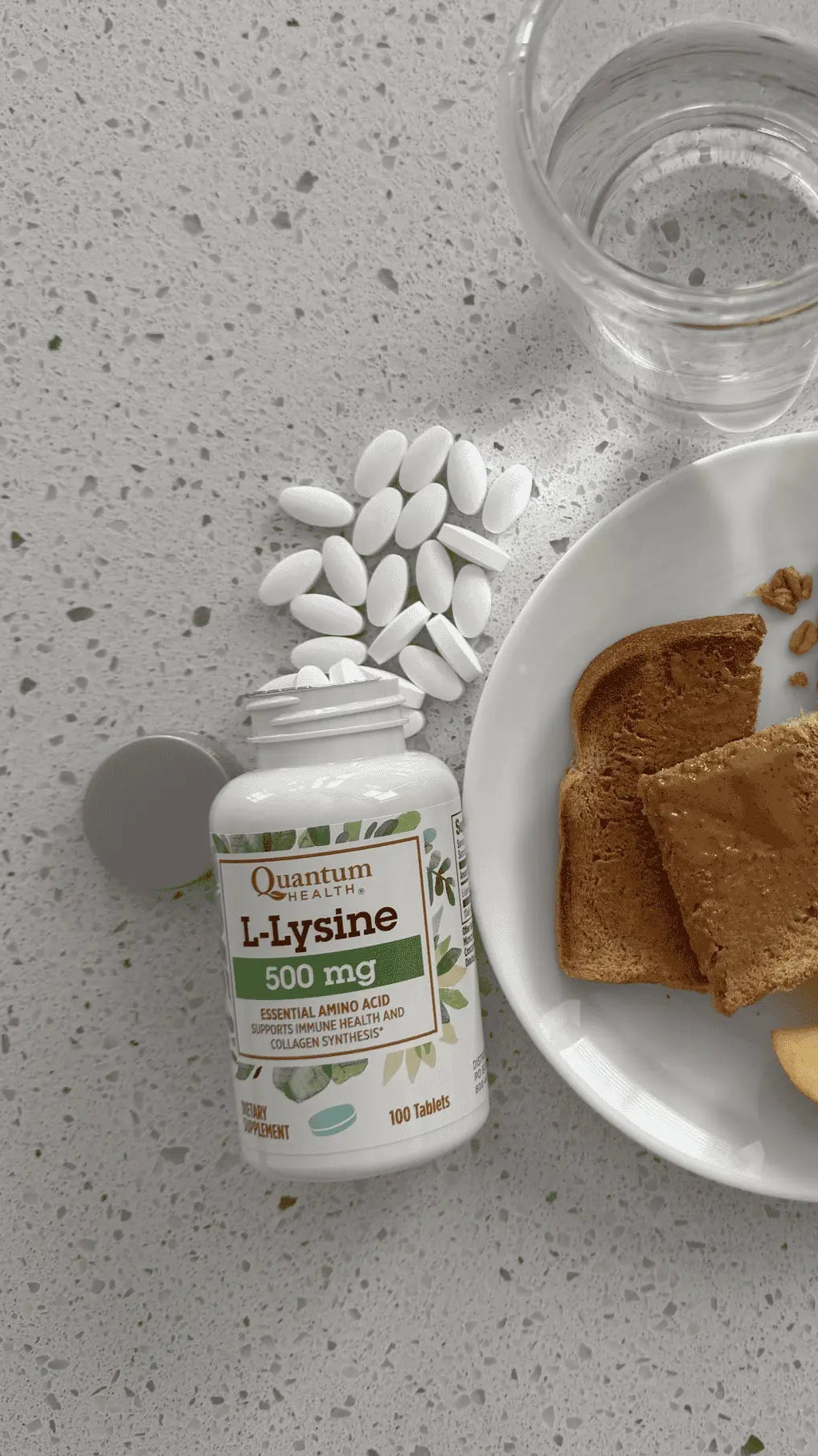 Vitamin bottle, glass of water, plate with toast, nuts, and apples on a gray surface